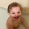 toddler, child, bath, water, smile, happy, wet_hair, skin, face, curly_hair, rosy_cheeks, sitting, indoor, young_child, infant, cute, joyful, playful, bath_time, naked