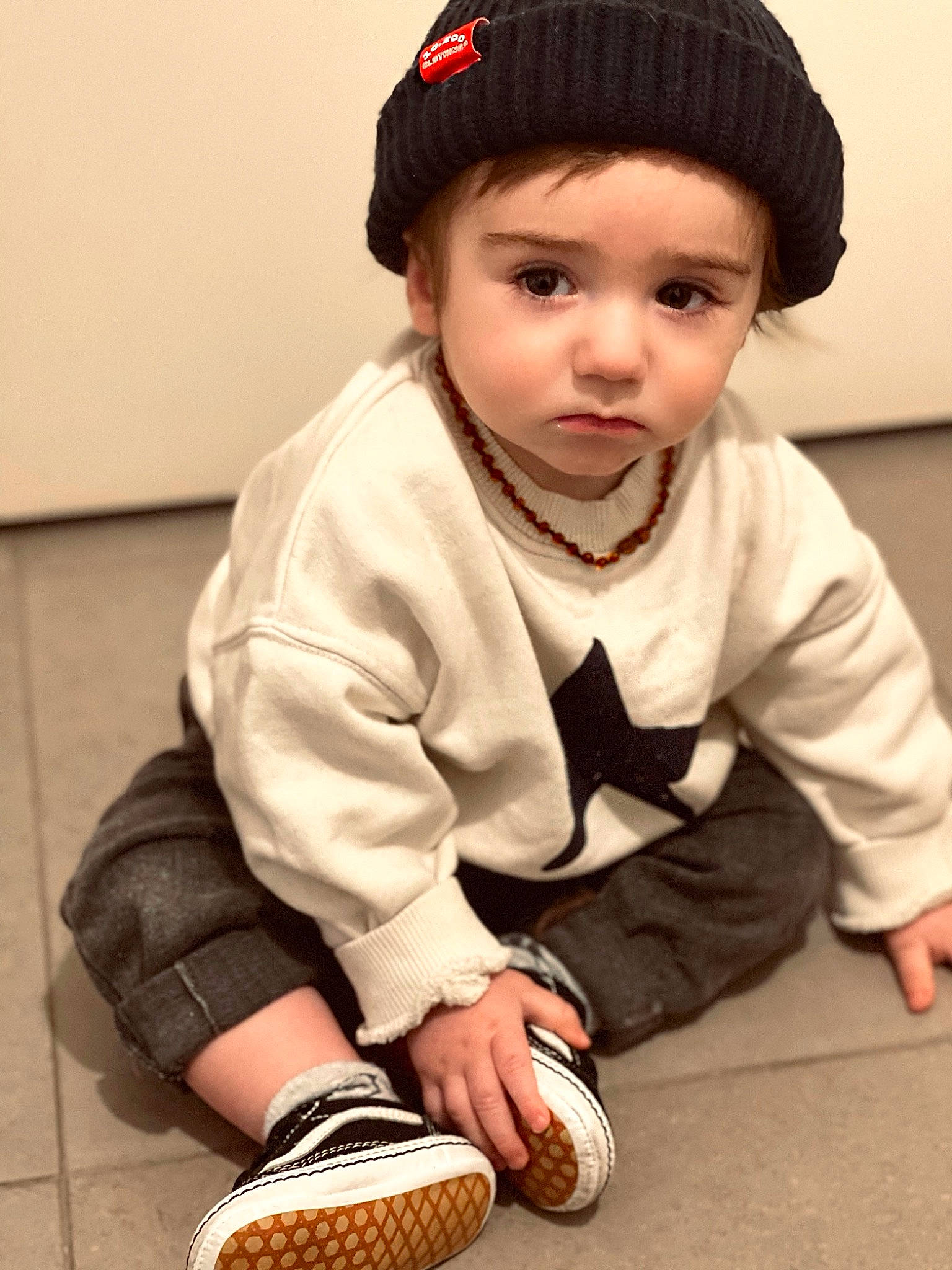 Marius participe au concours pour gagner de l'argent avec cette photo : baby, baby_toddler_clothing, black, cap, child, costume_hat, face, fashion_accessory, flooring, footwear, fur, glove, grass, headwear, human_body, neck, outerwear, pattern, person, sitting