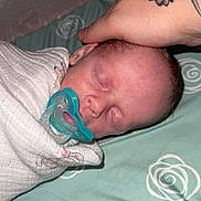 Carter is registered to the contest to win money with this photo: newborn, baby, sleeping, pacifier, blanket, hand, tattoo, bed, bed_sheet, pattern, close_up, infant, rest, comfort, swaddle, peaceful, skin, face, person, indoor