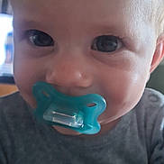 George is registered to the contest to win money with this photo: baby, child, pacifier, face, eyes, hand, clothing, indoor, portrait, cute, infant, person, closeup, skin, expression, holding, nail_polish, young_child, human, soft_light