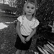 Kylianna a rejoint le concours — aidez-le/la à gagner de superbes lots ! bow, casual_clothing, child, curious_expression, daylight, girl, gravel, grill, hands_clasped, leaves, nature, outdoor, portrait, skirt, sneakers, standing, tree, white_top, wood, young