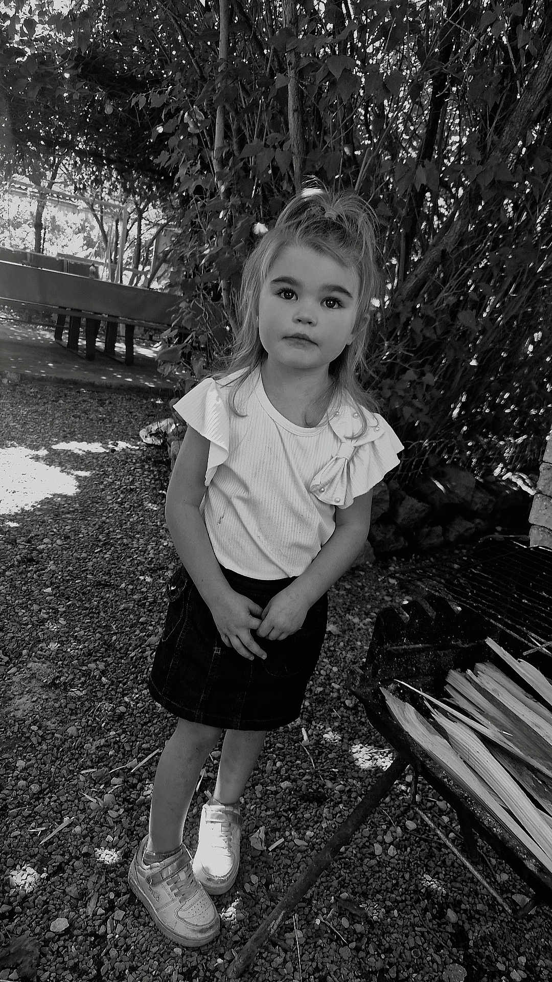 Kylianna a rejoint le concours — aidez-le/la à gagner de superbes lots ! bow, casual_clothing, child, curious_expression, daylight, girl, gravel, grill, hands_clasped, leaves, nature, outdoor, portrait, skirt, sneakers, standing, tree, white_top, wood, young