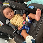 Denym joined the competition — help win amazing prizes! baby, sleeping, car_seat, child, infant, yellow_shirt, blue_shorts, sock, foot, stripes, plaid, indoor, resting, peaceful, young_child, seatbelt, black_car_seat, curly_hair, toddler, naptime