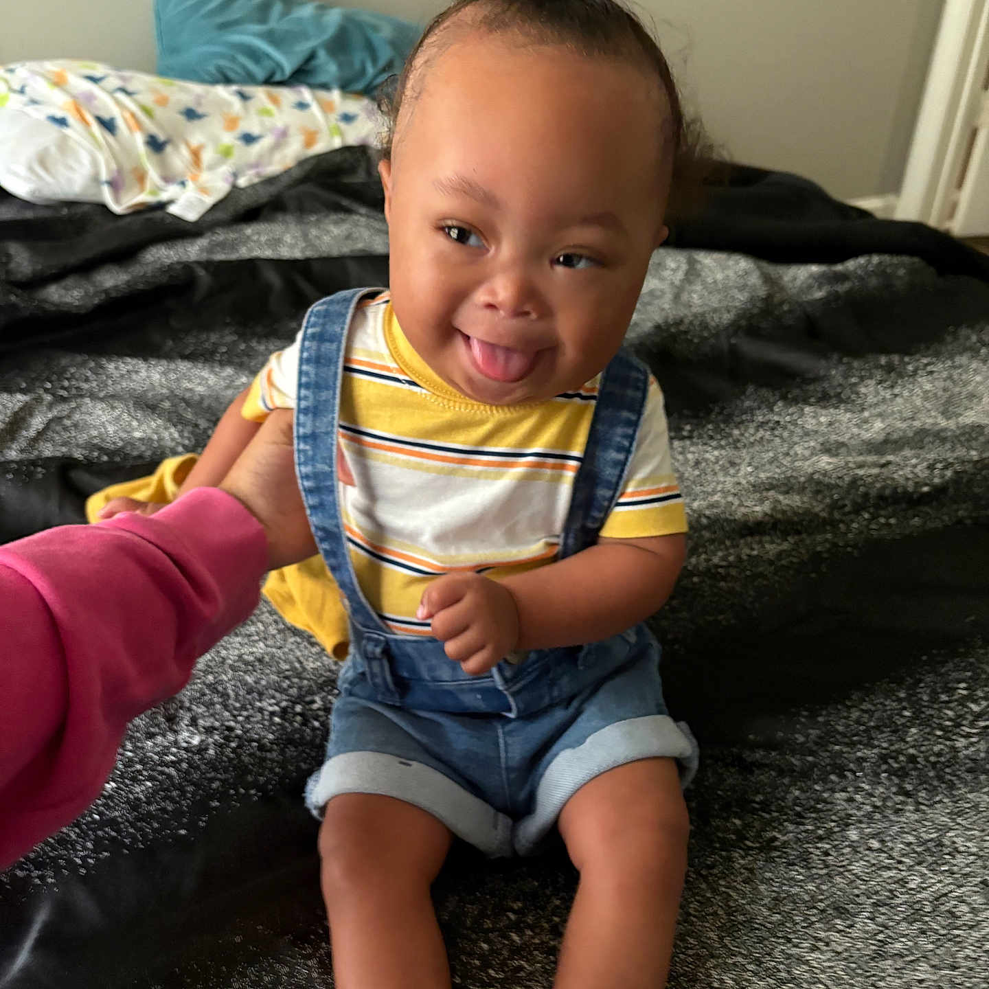Denym joined the competition — help win amazing prizes! baby, bed, blanket, child, clothing, cute, denim_overalls, face, hair_bun, hand, happy, indoor, person, playful, skin, smiling, socks, striped_shirt, toddler, tongue_out