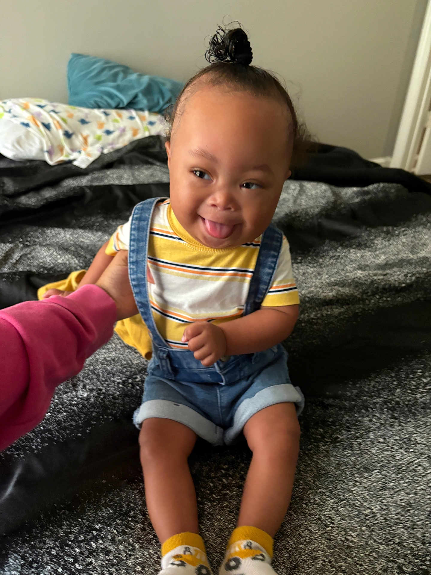 Denym joined the competition — help win amazing prizes! toddler, child, smiling, tongue_out, denim_overalls, striped_shirt, socks, bed, blanket, hand, person, indoor, hair_bun, playful, happy, cute, clothing, baby, skin, face