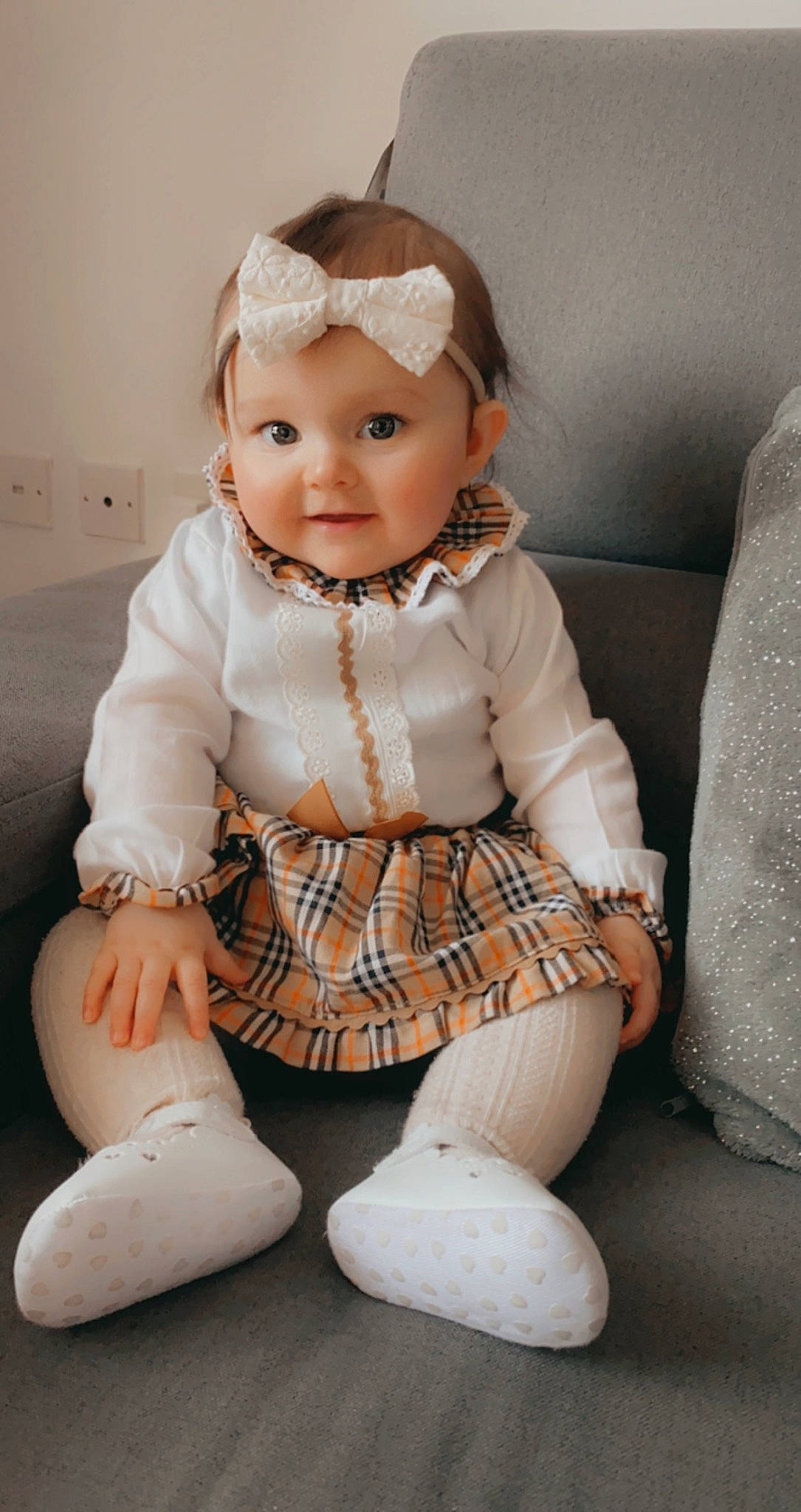 Evelyn is registered to the contest to win money with this photo: arm, baby_toddler_clothing, child, doll, dress, embellishment, eye, eyelash, headgear, headwear, human_leg, jewellery, leg, pattern, person, skin, sleeve, textile, thigh, toy