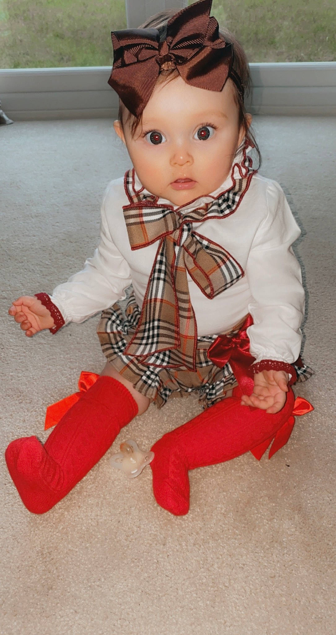 Evelyn joined the competition — help win amazing prizes! baby, baby_toddler_clothing, child, collar, doll, dress_shirt, eyelash, flooring, fur, head, human_body, outerwear, pattern, person, plaid, sitting, skin, sleeve, tartan, toddler