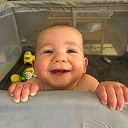 Elijah is registered to the contest to win money with this photo: baby, child, smile, happy, playpen, toys, indoor, face, hands, cheeks, teeth, person, infant, cute, home, furniture, colorful, joyful, closeup, portrait
