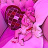 Elijah is registered to the contest to win money with this photo: baby, blanket, chair, child, cozy, cushion, cute, happy, heart_shaped, indoor, infant, onesie, person, pink, plush, portrait, seated, smiling, socks, soft
