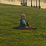 Elijah is registered to the contest to win money with this photo: child, toddler, grass, blanket, smile, outdoor, pond, water, sunset, nature, park, happy, baby, greenery, sky, reflection, casual_clothing, sitting, daylight, peaceful