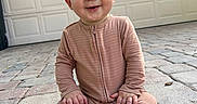 Elijah is registered to the contest to win money with this photo: baby, barefoot, casual_clothing, child, cute, daylight, driveway, drool, front_view, garage_door, happy, infant, onesie, outdoor, pavement, person, portrait, sitting, smile, young_child