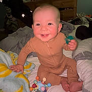 Elijah joined the competition — help win amazing prizes! baby, child, smiling, bed, blanket, toy, indoor, onesie, person, happy, face, furniture, television, dresser, home, infant, cute, sitting, playful, room