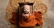 Elijah is registered to the contest to win money with this photo: newborn, baby, infant, wooden_bed, orange_blanket, teddy_bear, woven_mat, swaddled, peaceful, sleeping, cute, portrait, baby_bedding, soft_texture, hand, head, face, background, cozy, decor