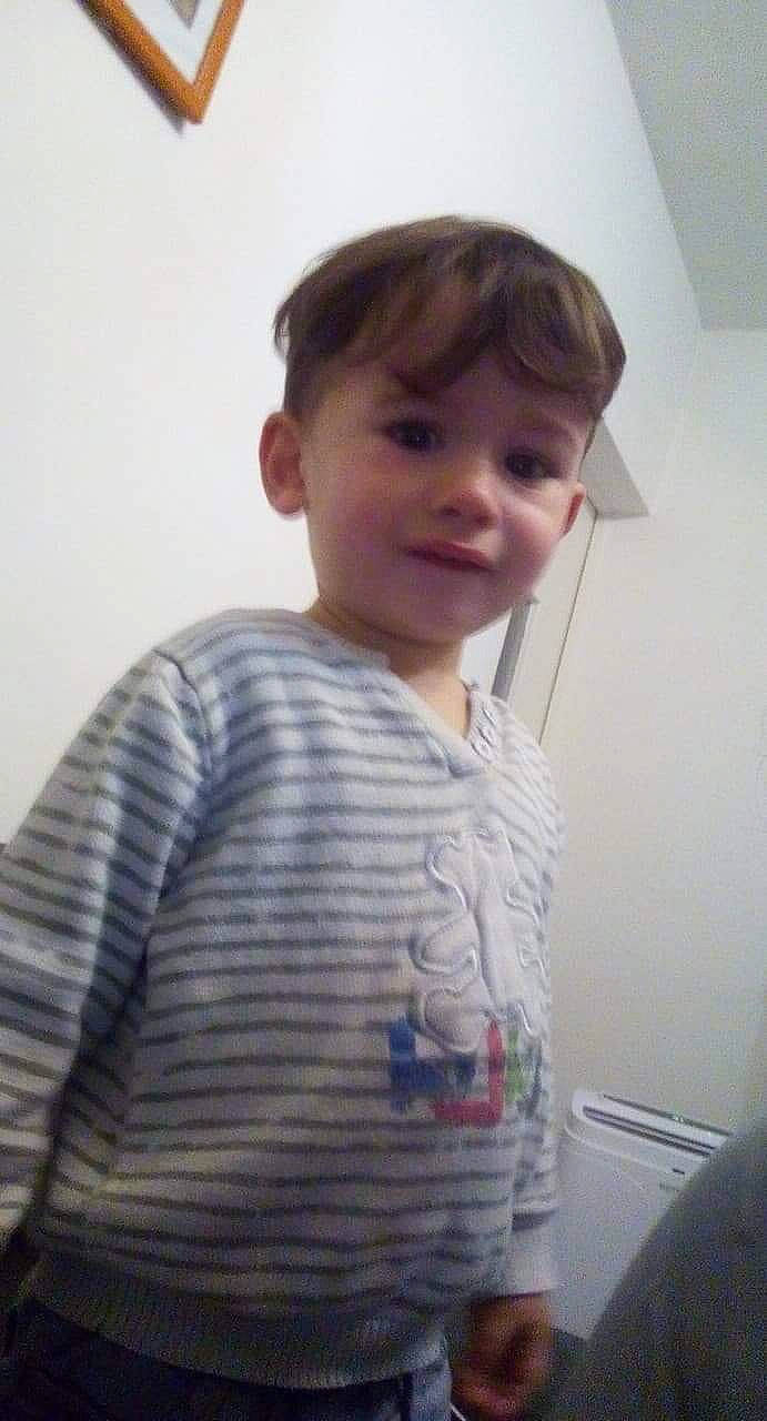 Kenzo participe au concours pour gagner de l'argent avec cette photo : arm, cheek, child, chin, ear, forehead, hair, hairstyle, neck, nose, outerwear, person, shoulder, sleeve, smile, standing, t_shirt, toddler