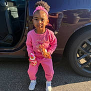 Jhordyn is registered to the contest to win money with this photo: child, girl, pink_clothing, headband, curly_hair, snack, drink, car, car_door, tarmac, sneakers, outdoor, sunlight, standing, casual, young_child, person, daylight, parking_lot, reflection