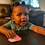 Jhayde joined the competition — help win amazing prizes! toddler, child, face, hair_buns, hand, table, striped_object, living_room, couch, blurred_background, indoor, person, expression, cute, skin, clothing, short_sleeves, furniture, smiling, curious