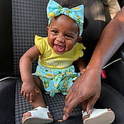 Jhayde is registered to the contest to win money with this photo: baby, child, smiling, headband, yellow_clothing, blue_clothing, car_seat, sandals, hand, person, happy, cute, infant, sitting, footwear, portrait, indoor, skin, human, playful