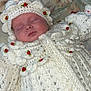 baby, sleeping, crocheted_clothing, white_outfit, red_roses, blanket, floral_pattern, infant, cute, peaceful, soft_texture, handmade, knitted, face, headwear, newborn, portrait, resting, indoors, adorable