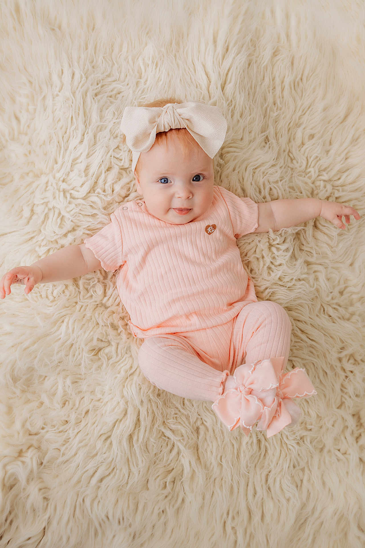 Maeve joined the competition — help win amazing prizes! baby, infant, child, pink_clothing, bow, headband, smiling, blue_eyes, fluffy_rug, soft_texture, cute, happy, portrait, lying_down, indoor, cozy, comfortable, fashion, adorable, person