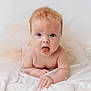 Maeve is registered to the contest to win money with this photo: baby, infant, child, tutu, blanket, soft, cute, portrait, light_hair, blue_eyes, expression, lying_down, curious, skin, chubby, indoors, white_background, clothing, person, adorable
