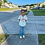 Hayliana is registered to the contest to win money with this photo: child, smiling, sidewalk, suburban, tshirt, cat_graphic, jeans, sneakers, grass, houses, cars, daytime, blue_sky, happy, outdoor, curly_hair, person, street, residential_area, casual_clothing