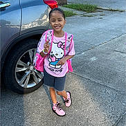 Hayliana joined the competition — help win amazing prizes! child, smiling, outdoor, sidewalk, car, hello_kitty, pink_boots, backpack, peace_sign, shorts, tshirt, bracelet, sunlight, concrete, grass, fence, happy, person, shoe_laces, casual