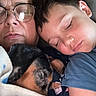 person, child, dog, sleeping, glasses, blanket, couch, closeup, rest, family, nap, indoor, comfort, affection, cozy, portrait, tired, relax, casual_clothing, bond