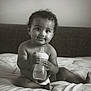 Roy participe au concours pour gagner de l'argent avec cette photo : baby, child, infant, bottle, bed, diaper, black_and_white, curly_hair, cute, smiling, tongue_out, indoors, portrait, sitting, soft_light, expression, person, young, nursery, cozy