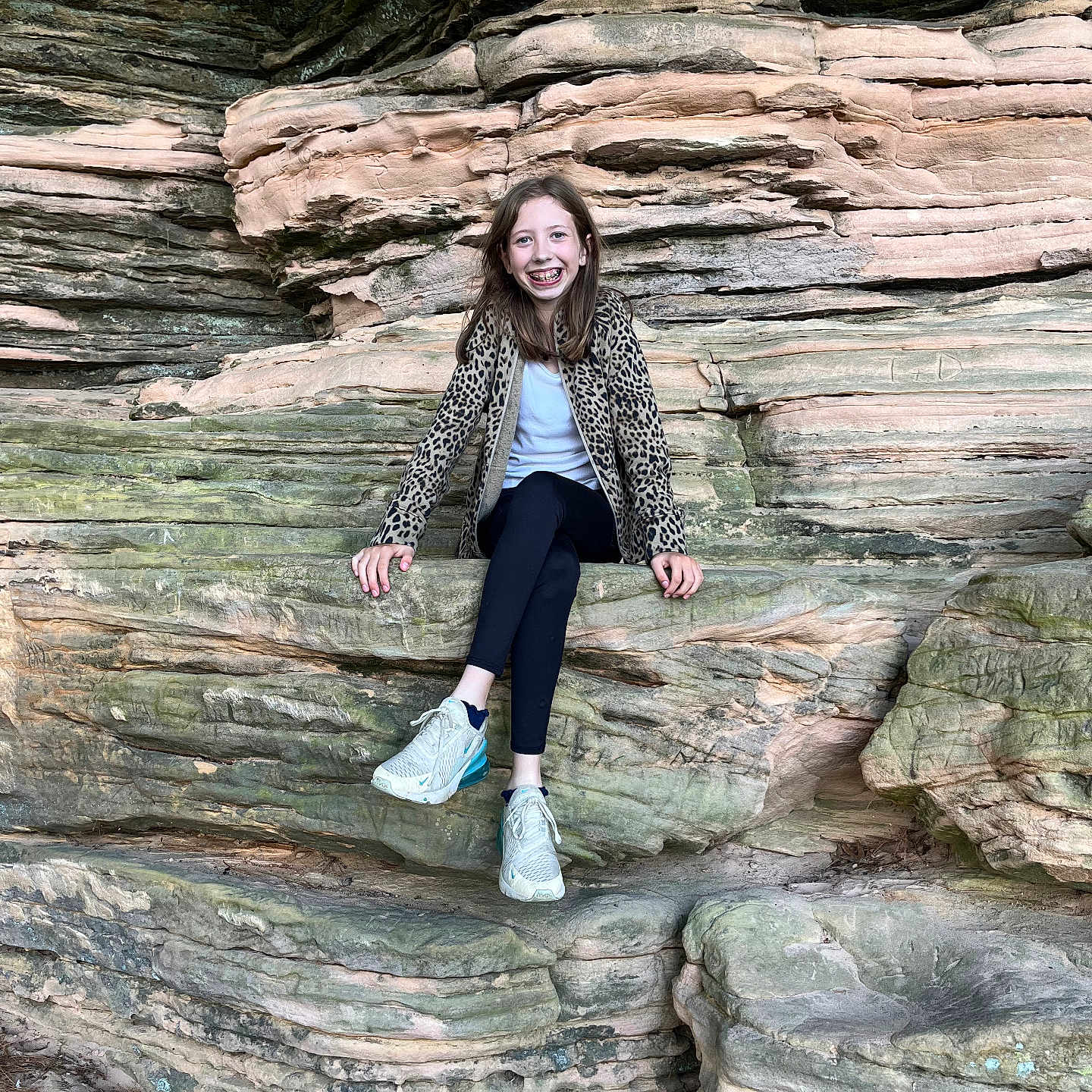 Aubrey joined the competition — help win amazing prizes! child, girl, smile, braces, leopard_print, jacket, rock, rocks, natural, outdoor, nature, sitting, casual, footwear, sneakers, legs_crossed, happy, portrait, scenery, daylight
