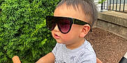 David joined the competition — help win amazing prizes! toddler, child, sunglasses, stroller, outdoor, greenery, bush, handlebar, person, casual_clothing, short_sleeve_shirt, blue_shorts, side_profile, daylight, curly_hair, skin, seat, playful, baby, young_child