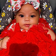 Joeniyah is registered to the contest to win money with this photo: baby, infant, child, red_dress, headband, strawberry_pattern, floral_cushion, cute, adorable, closeup, portrait, indoors, soft_lighting, chubby_arms, sitting, fashion, colorful, young, face, expression