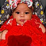 baby, infant, child, red_dress, headband, strawberry_pattern, floral_cushion, cute, adorable, closeup, portrait, indoors, soft_lighting, chubby_arms, sitting, fashion, colorful, young, face, expression