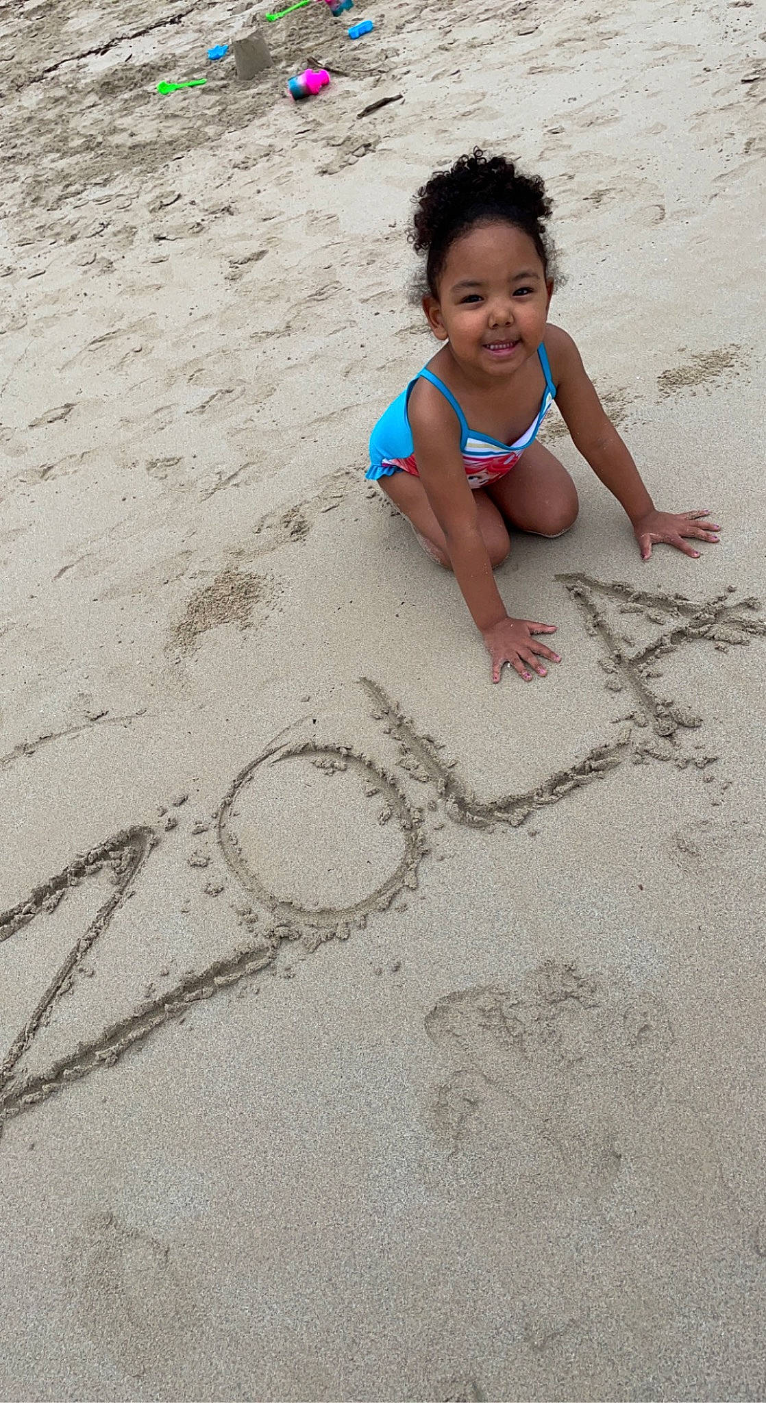 Zola is registered to the contest to win money with this photo: barefoot, beach, body_of_water, child, eye, flooring, foot, fun, handwriting, happy, human_leg, joy, leisure, people_in_nature, people_on_beach, person, play, sand, smile, soil