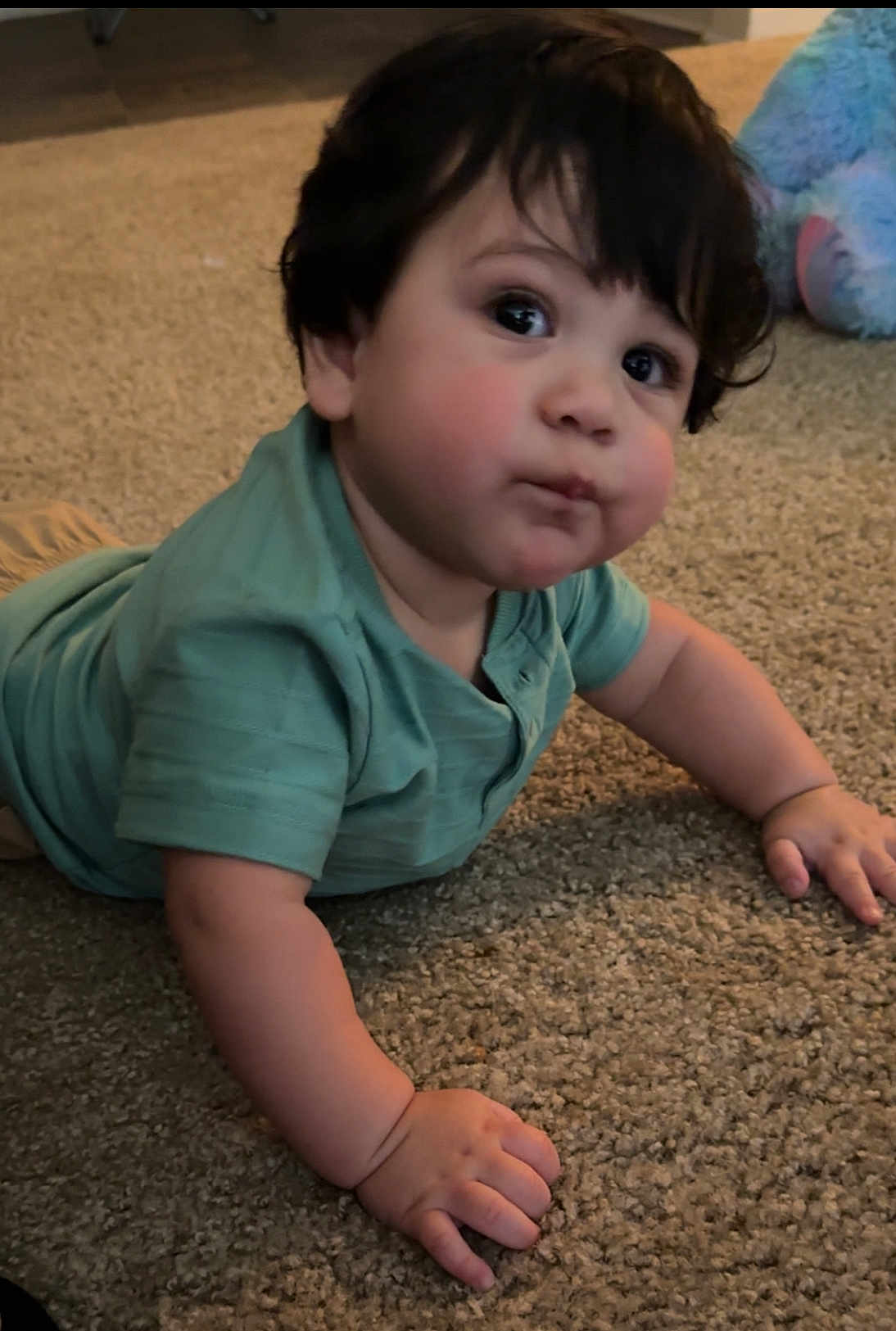 Aiden is registered to the contest to win money with this photo: baby, child, infant, carpet, indoor, crawling, curious, cute, face, hand, dark_hair, green_shirt, soft_lighting, portrait, expression, young_child, floor, skin, person, toddler