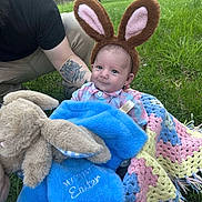 Trenton joined the competition — help win amazing prizes! baby, bunny_ears, crochet_blanket, plush_blanket, tattoo, outdoor, grass, person, cute, smiling, child, easter, blue_blanket, pink_shirt, headwear, nature, greenery, infant, happy, sitting