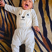 Syeda is registered to the contest to win money with this photo: baby, infant, smiling, laughing, white_clothing, hat, lying_down, blanket, patterned_blanket, zebra_stripes, cute, happy, child, one_person, indoors, portrait, playful, fun, cozy, comfortable