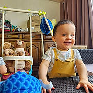 Milo participe au concours pour gagner de l'argent avec cette photo : toddler, child, smiling, indoor, toy, stuffed_animal, furniture, table, curtains, window, clothing, happy, face, baby, person, wooden_cabinet, plush, home, play, cute