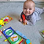 baby, child, smiling, toy, carpet, fabric_book, orange_toy, blue_carpet, indoor, playtime, pacifier, clothing, infant, cute, colorful, floor, lying_down, happy, young_child, playthings