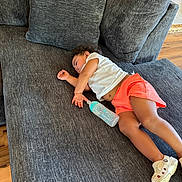 Jazminñ is registered to the contest to win money with this photo: toddler, child, sleeping, couch, sofa, bottle, white_shirt, coral_shorts, indoor, living_room, wooden_floor, footwear, relaxing, nap, pillow, home, furniture, person, casual_clothing, resting