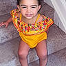 Jazminñ is registered to the contest to win money with this photo: toddler, child, stairs, carpet, yellow_outfit, colorful_embroidery, pink_socks, curly_hair, smiling, sitting, indoors, person, young_child, happy, cute, playful, portrait, casual, small_child, baby