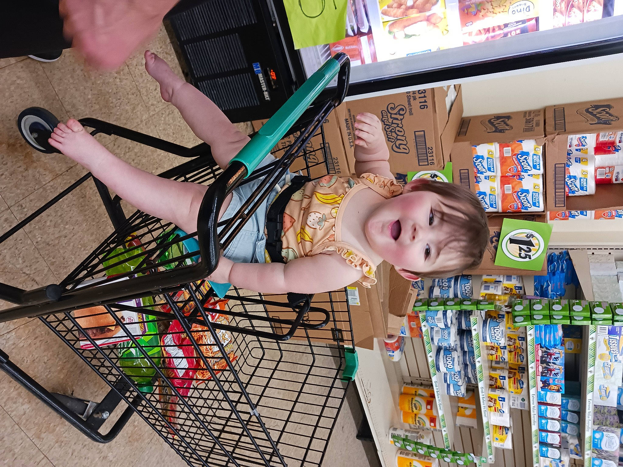 Melody is registered to the contest to win money with this photo: beauty, building, cart, child, convenience_store, fun, human_leg, leisure, pattern, person, play, publication, retail, sandal, shelf, shopping, t_shirt, thigh, tire, toddler