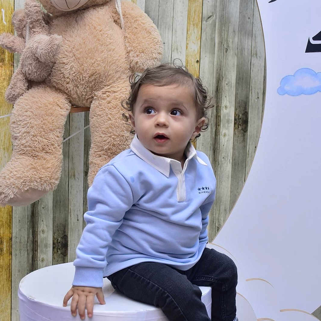 Isaac participe au concours pour gagner de l'argent avec cette photo : boy, child, clothing, coat, face, footwear, head, indoors, interiordesign, jeans, male, pants, person, photography, portrait, shoe, sitting, sneaker, teddybear, toy