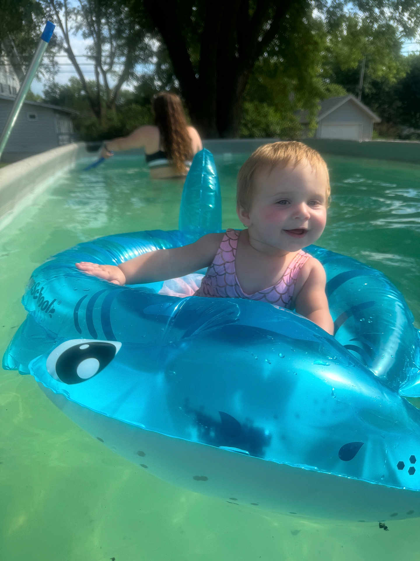 Evelyn is registered to the contest to win money with this photo: toddler, child, pool, inflatable, float, water, summer, outdoor, toy, swimming, fun, happy, person, tree, house, sunlight, nature, blue, pink, swimsuit