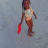 Genesis is registered to the contest to win money with this photo: child, beach, sand, shovel, water, ocean, footprints, swimsuit, braids, toy, summer, vacation, outdoor, sky, people, buildings, shoreline, play, holiday, sunset