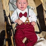 Sidjil participe au concours pour gagner de l'argent avec cette photo : baby, blanket, bow_tie, child, comfort, cozy, cute, fabric, face, footwear, furniture, indoor, infant, person, portrait, red_pants, relaxed, stroller, suspenders, white_shirt