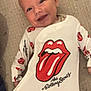 Sidjil a rejoint le concours — aidez-le/la à gagner de superbes lots ! baby, infant, smile, face, onesie, clothing, rolling_stones, tongue_logo, white, red, lying_down, cute, happy, portrait, child, apparel, soft_light, indoor, human, baby_garment