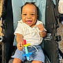 Nhyree joined the competition — help win amazing prizes! baby, child, smiling, happy, toy, stroller, clothing, white_shirt, shorts, indoor, carpet, seat, cute, playful, infant, portrait, person, hand, face, fun