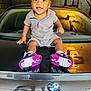 Nhyree is registered to the contest to win money with this photo: automobile, bmw, car, casual_clothing, child, concrete_wall, footwear, garage, happy, head, indoor, license_plate, person, portrait, reflection, sitting, smiling, sneakers, toddler, young_child