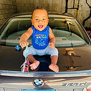 Nhyree is registered to the contest to win money with this photo: automobile, baby, blue_shirt, bmw, car, child, clothing, concrete_wall, foot, garage, happy, indoors, keys, license_plate, person, reflection, sitting, smiling, trunk, young_child