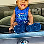 baby, child, smiling, blue_clothing, blue_shoes, car, bmw_logo, trunk, garage, happy, sitting, closeup, cute, infant, person, portrait, casual, indoor, playful, fashion